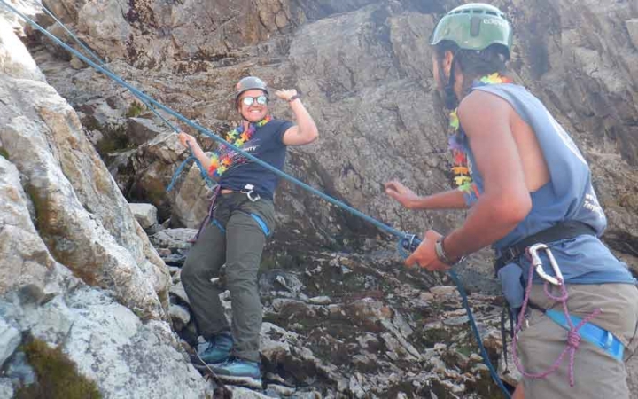 two gap year students preparing to rock climb go to high five one another on an outward bound outdoor educator course